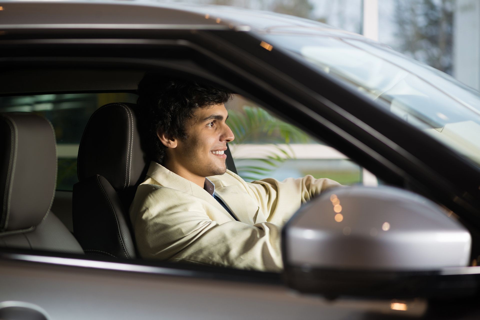 Young handsome man at show room sitting in car